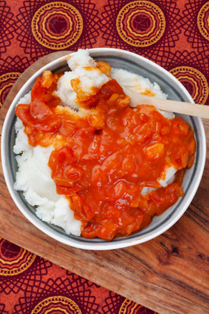 Traditional South African pap or maize meal with traditional sauce of tomato and onion on traditional textileの写真素材