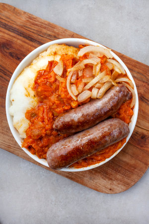 Traditional South African Pap and Wors, sausage with popular maize meal staple covered with Chakalaka or relish on mottled gray with copy spaceの写真素材