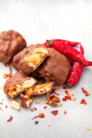 Chocolate covered peanut brittle pieces with chili, a spicy twist on greyの写真素材