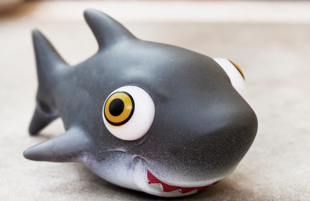 Funny black shark toy with big eyes on gray concrete background.の写真素材