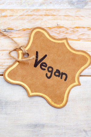 Vegan handwritten on vintage gift tag with rustic wooden surfaceの写真素材