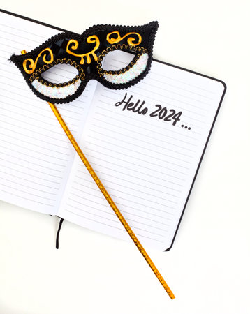 Notebook with hello 2024 written on it with carnival mask on whiteの写真素材