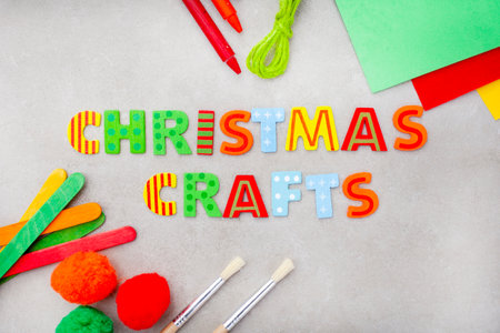 Christmas crafts in bright lettering with colorful craft supplies on a mottled grey surfaceの写真素材