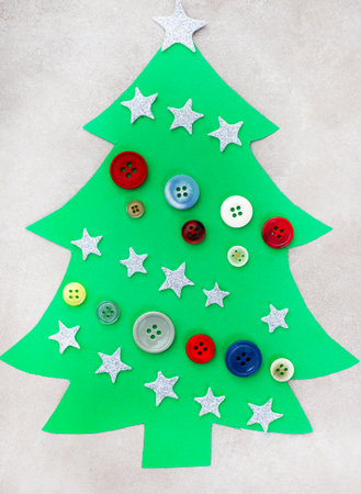 Christmas tree made of green paper with buttons and stars on a light backgroundの写真素材