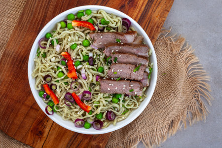 Noodles with beef and vegetables in a bowl on the table
