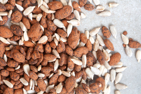 Mixture of plain sunflower seeds and cocoa dusted sunflower and pumpkin seeds, on mottled grey with...