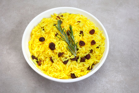 Traditional South African yellow rice, made with turmeric and raisins with rosemary garnish, In...