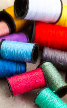 Colorful spools of thread for sewing on a gray background.