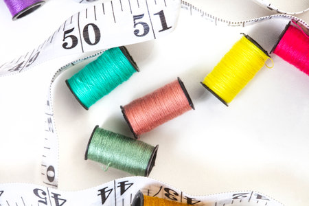 Sewing threads and measuring tape on a white background close-up