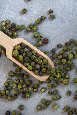 Green peppercorns in a wooden spoon on a gray background.の写真素材