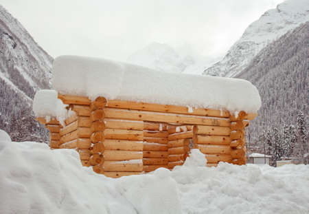 unfinished log cabin among snowdriftsの写真素材