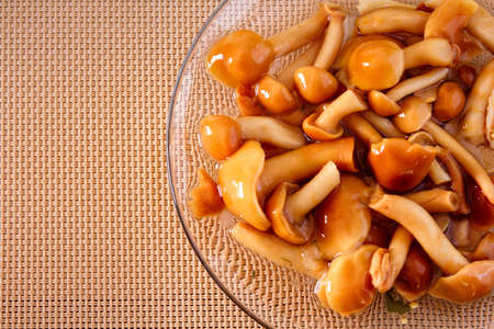 marinated mushrooms on a glass plate on a wicker backgroundの写真素材