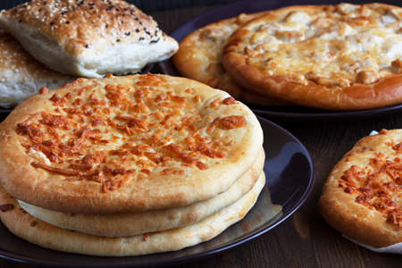 Different kinds of baked pies on a dark table surface