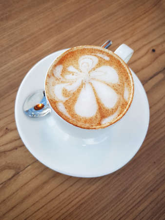 Cup cappuccino (with a flower pattern on the surface) on a wooden tableの写真素材