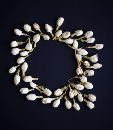round decorative frame of dried jasmine flower buds on black backgroundの写真素材