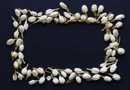Rectangular frame of dried jasmine flower buds on a black backgroundの写真素材