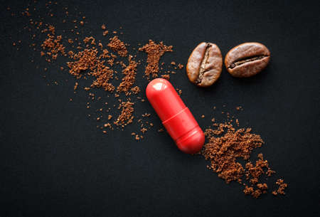 red pill and coffee beans on a black background, the concept of drugs containing caffeineの写真素材