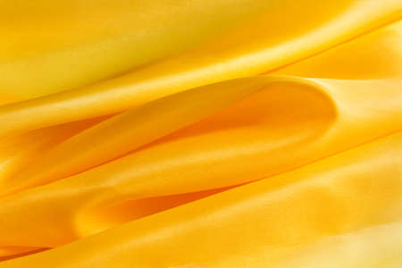 yellow bright fabric with large folds, abstract backgroundの写真素材