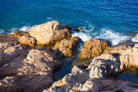 sea and coastal rocks illuminated by the setting sun in Spain, Cataloniaの写真素材