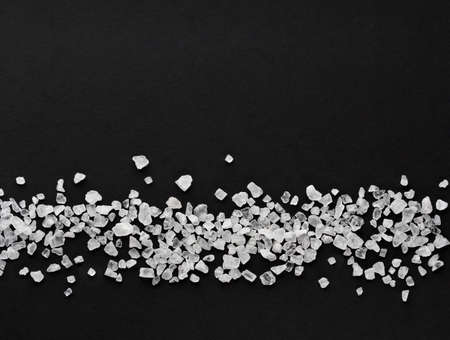 coarse sea salt scattered in a horizontal line on a black background with place for text