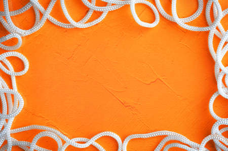 frame with white rope on  bright orange background,  focus on the rope