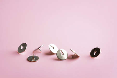 push pins scattered on pink background with copy space, metal thumbtacksの写真素材