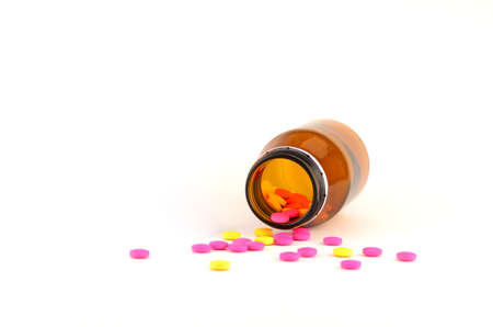 pills spilling out of bottle isolated on whiteの写真素材