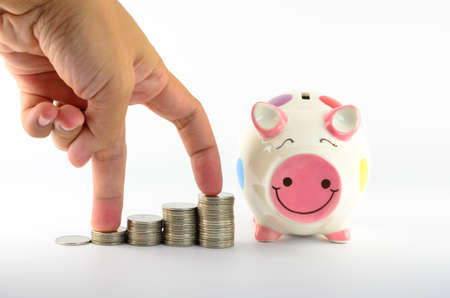 Piggy bank and hand with stacks of coins の写真素材