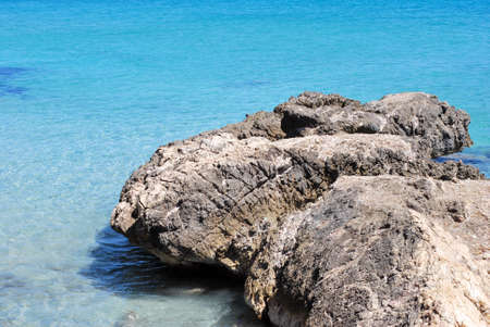 Landscape of a rock on the blue crystal calm sea 