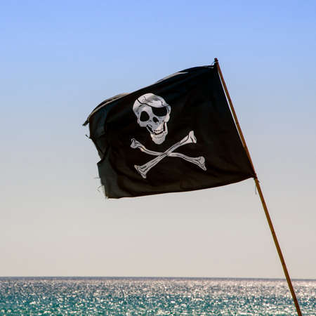 pirate flag waving with blue sea backgroundの写真素材