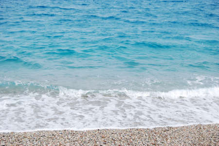 transparent deep blue wave of the sea that breaks on the shore with white foam and sand for summertimeの写真素材