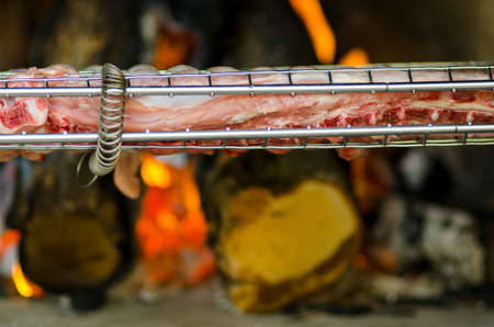 Grill with meat for barbecue and fire in background for dinnerの写真素材