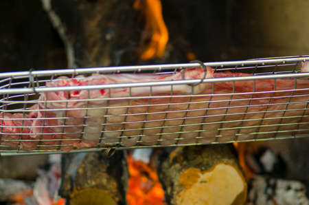 Grill with meat for barbecue and fire in background for dinnerの写真素材