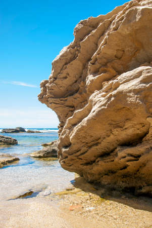 Golden rock in the seashore with clear blue sky seen from the left in Sardiniaの写真素材