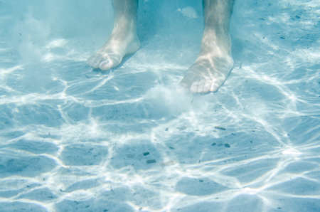 Male feet details underwater in the sea on the sandの写真素材