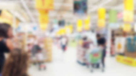blurred interior of supermarket with people shopping as background