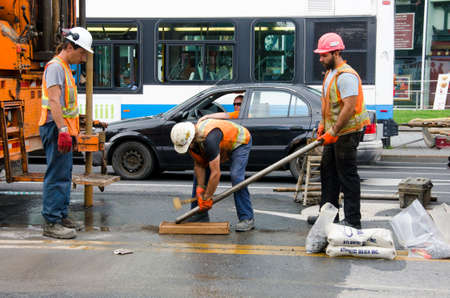 Montreal, Quebec, Canada- July 19 2016 - road repair laborers crew with heavy machinery working in the center of the street as editorialのeditorial素材