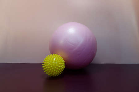 Pink rubber ball for sports and Yellow massage ball with needles on a purple and pink backgroundの写真素材