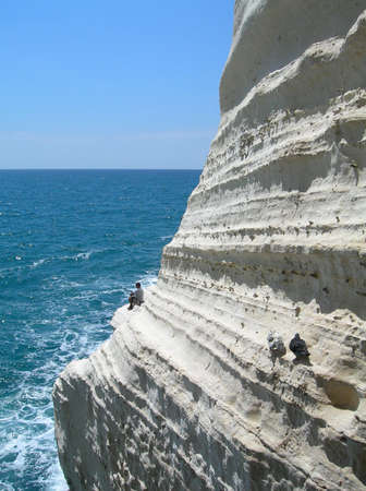 Fisherman and birds on white cliff          