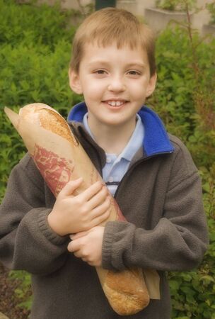 Young French boy holding a loaf of bread - le pain.の写真素材