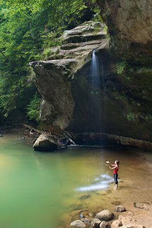Woman standing beneath a waterfall with her hands uplifted.の写真素材