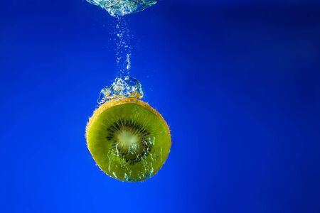 Fresh kiwi slice falling into water. A delicious and nutritious snack.の写真素材