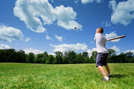 Young Caucasian boy playing baseball in a sunny field on a beautiful summer day.