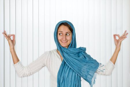 Beautiful young woman posed with a blue scarf and a fun expression.の写真素材