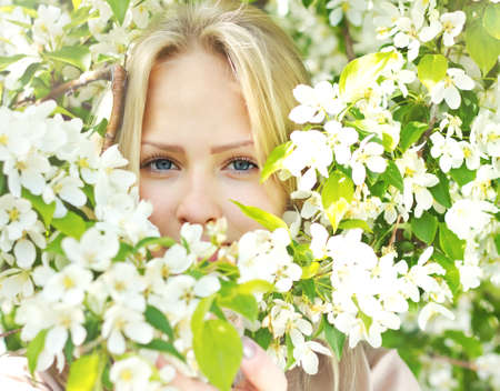 Closeup beautiful  woman face among blossom  tree branches