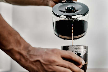 A man pouring coffee from a pot to a mug 3の写真素材