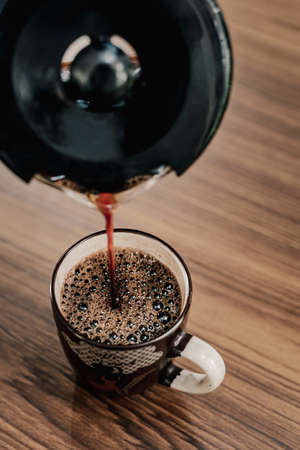 A man pouring coffee to a mugの写真素材