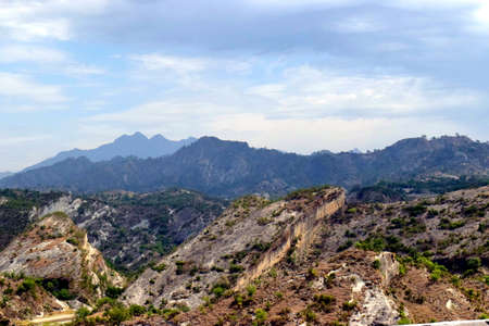 A landscape with layers of mountains, blue sky and clouds