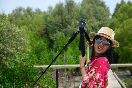Thai woman portrait with tripod on the bridge in Mangrove forest or Intertidal forest at...