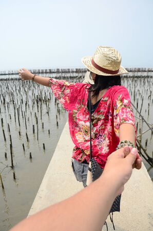 Thai woman lead someone by the hand and hold on the walkway bridge in Mangrove forest or Intertidal forest at Bangkhunthein in Bangkok Thailand.の写真素材
